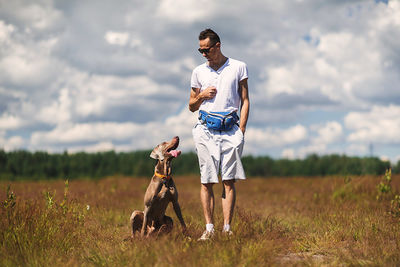 Man with dog standing on field