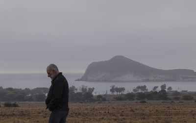 Side view of adult man on seaside against rock and sky in winter. cabo de gata park, almeria, spain