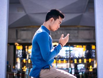 Side view of young man looking at illuminated building