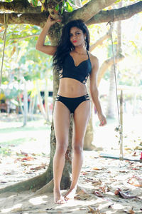 Portrait of beautiful young woman in bikini standing against wall