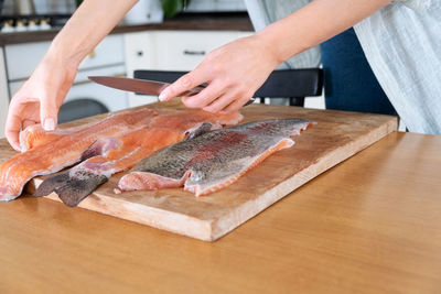 Female hands cutting fillet of red fish. red caviar. removing fish bones. butchering red fish meat.