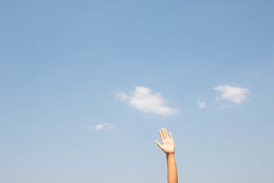 Low angle view of person hand against sky