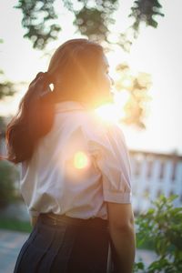 Woman standing against sky in sunny day