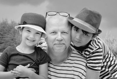 Portrait of grandfather with grandchildren against sky