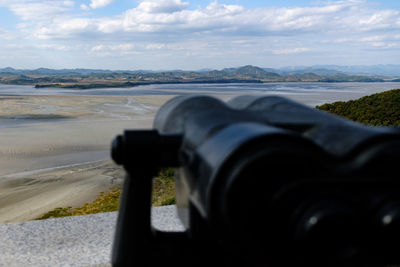 Cropped image of man photographing sea against sky