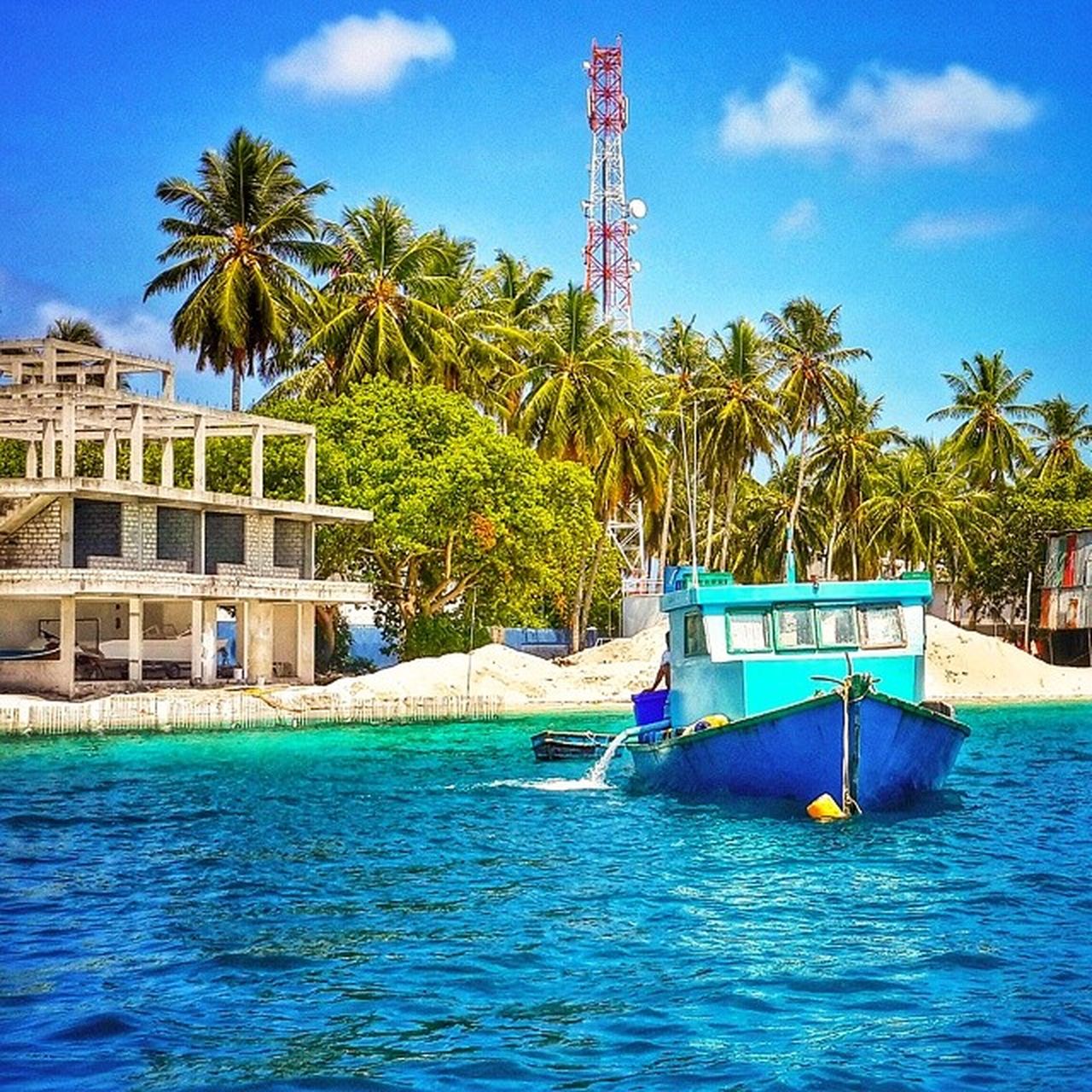 water, palm tree, tree, blue, waterfront, built structure, building exterior, architecture, sky, sea, swimming pool, nautical vessel, transportation, boat, rippled, mode of transport, day, cloud, incidental people, outdoors