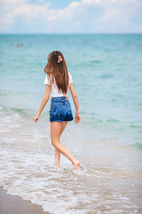 Rear view of woman standing at beach