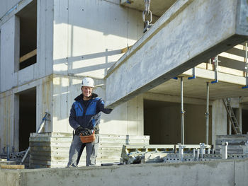 Smiling worker standing near construction material at site