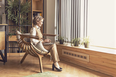 An elderly business woman in a  suit works in an office sitting in a chair.working at a computer