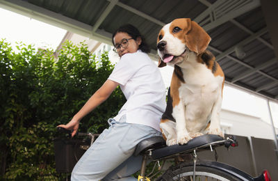 Portrait of woman with dog sitting on bicycle