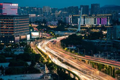 High angle view of light trails on road amidst buildings in city