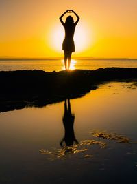 Silhouette man standing on beach against sky during sunset