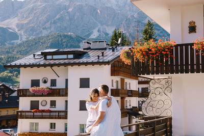 Woman standing by house against mountains