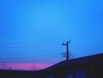 Low angle view of silhouette electricity pylon against clear blue sky