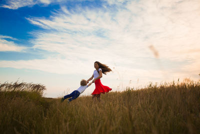 Rear view of women on field against sky
