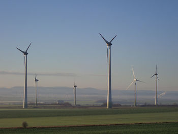 Windmills on field against sky