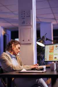 Side view of businesswoman using laptop while sitting on table