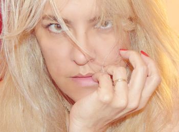 Portrait of young woman with blond hair biting nails
