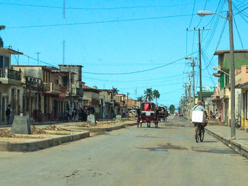 People on street amidst buildings against clear sky