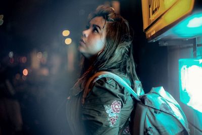 Young woman looking away in city at night