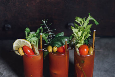 Bloody mary tomato brunch cocktail drink with celery, lemon, rosemary, pickles, olives, gold straw