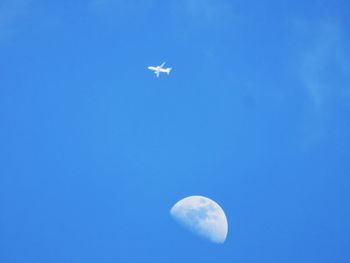 Low angle view of airplane flying against clear blue sky