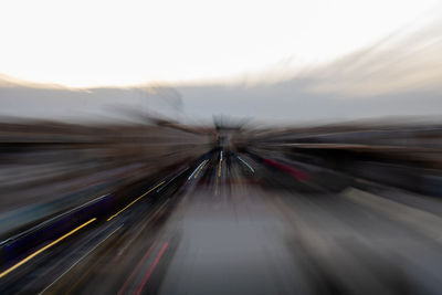 Light trails on road in city against sky during sunset