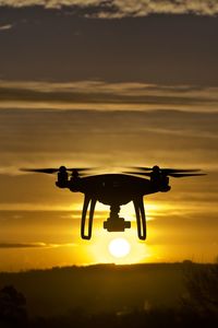 Close-up of silhouette helicopter against sky during sunset