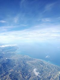 Aerial view of sea and landscape against blue sky