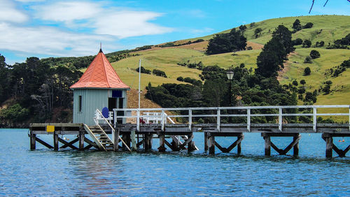 Built structure by lake and buildings against sky