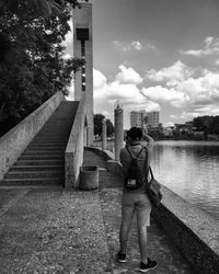 Rear view of man standing by building against sky