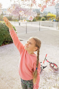 Portrait of cute girl playing with arms raised standing on street