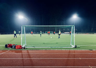 Group of people playing soccer on field at night