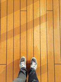 Low section of person standing on wooden floor