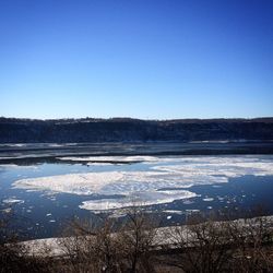 Snow covered landscape against clear blue sky
