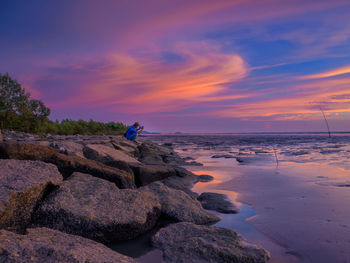 Man looking at sea against sky during sunset 