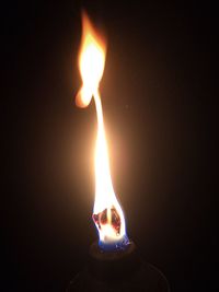 Close-up of lit candle in darkroom