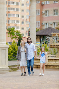 Full length portrait of smiling family walking in city