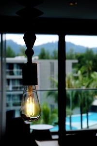 Close-up of light bulb hanging from window