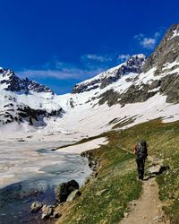 Rear view of man standing on snowcapped mountain against sky