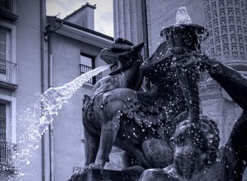 Low angle view of statue by fountain against building