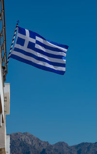 Low angle view of flag against blue sky