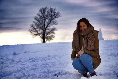Woman sitting on snow covered land