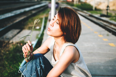 Woman holding plant while sitting outdoors