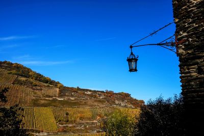 Low angle view of lighting equipment hanging on mountain against clear blue sky