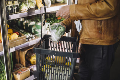 Midsection of senior man buying organic broccoli at grocery store