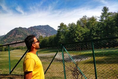 Side view of man standing on mountain against sky