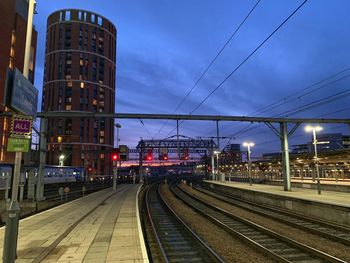 Railroad tracks in city against sky at dusk