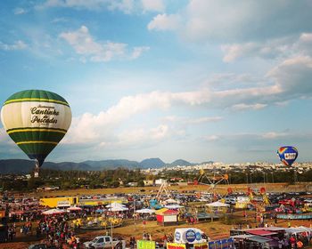 Illuminated hot air balloons in city against sky