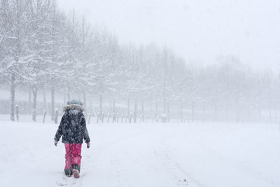 Rear view of girl walking on snow covered landscape